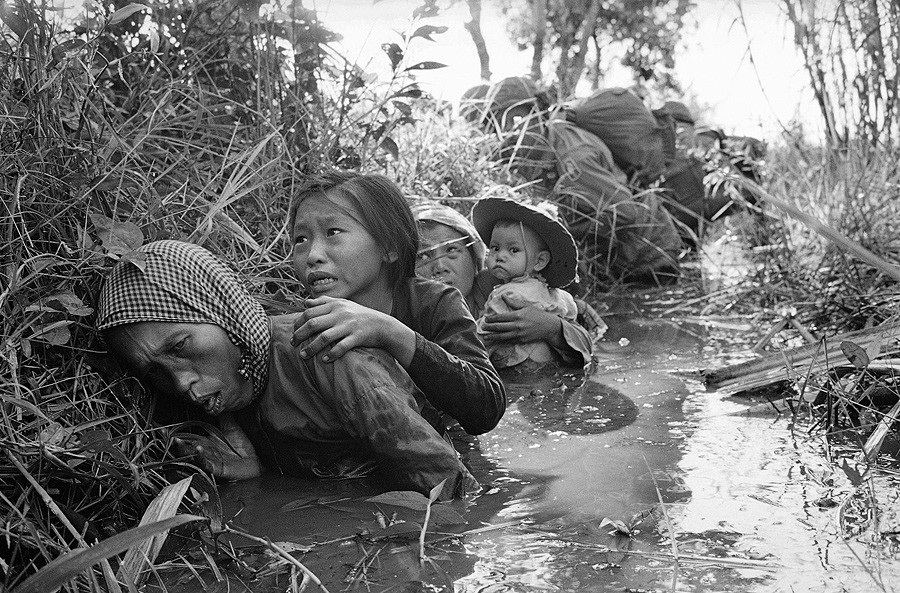 1 Women and children crouch in a muddy canal as they take cover from intense Viet Cong fire at Bao Trai, about 20 miles west of Saigon, Vietnam, on January 1, 1966 - Horst Faas.jpg